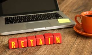 Laptop with blocks spelling "retain" in the foreground