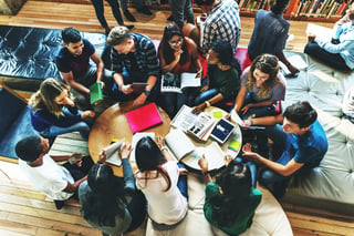 Students sitting around table with electronic devices